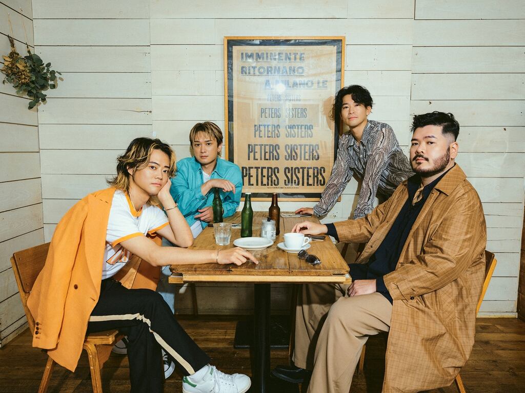 グラスやビール瓶が並ぶ木のテーブルを囲むFive New Oldメンバー4人