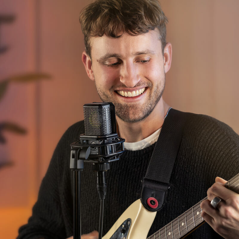 Man playing guitar and singing into a condenser microphone